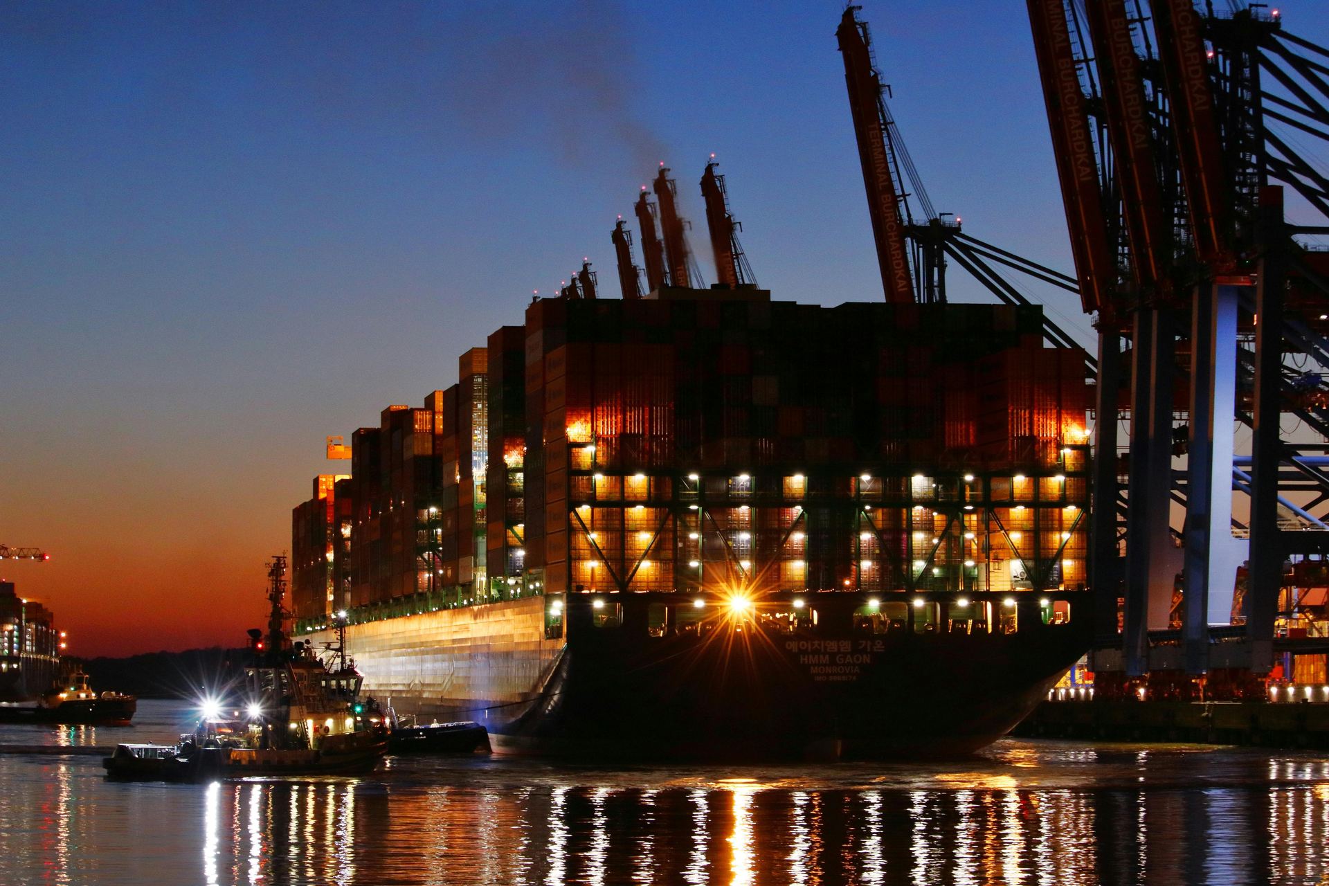 Container ship being loaded at a busy port at night